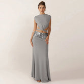 Woman wearing a gray two-piece dress with a sequined waistband on a plain background